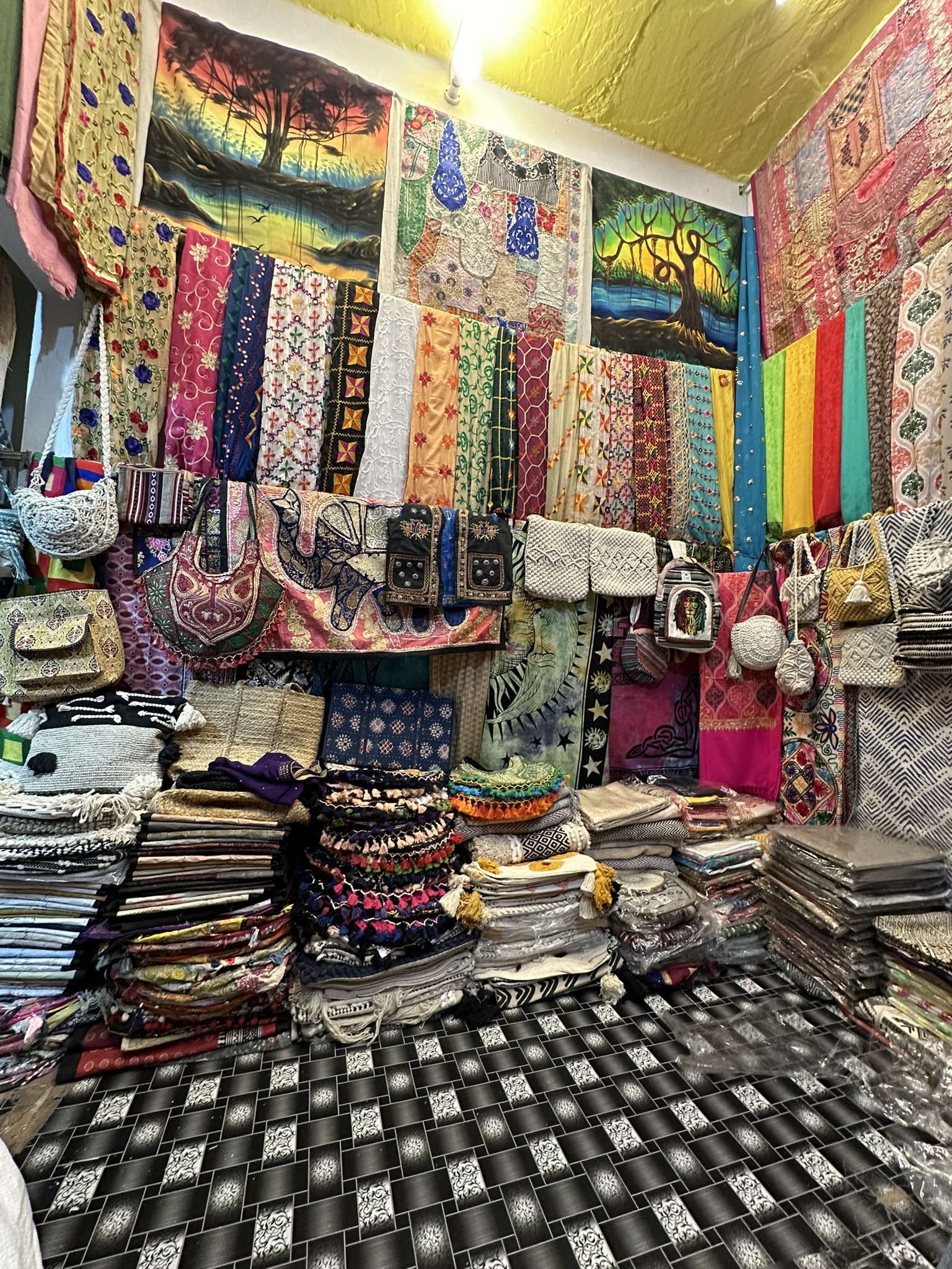 Indyjski bazar z kolorowymi tkaninami, torbami i dekoracjami rękodzielniczymi. Wzory i barwy.