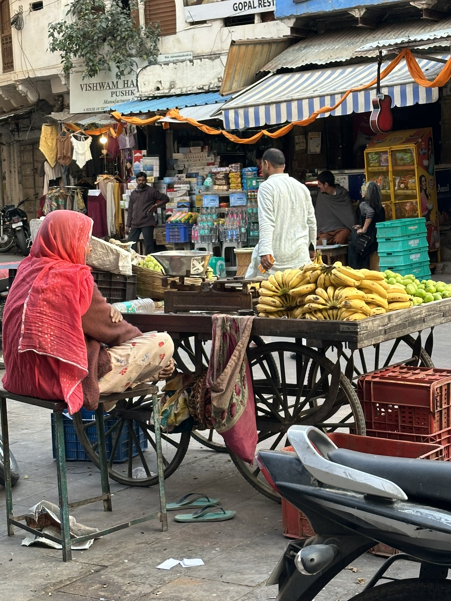 Kobieta w sari na bazarze w Pushkarze, obok wózka z bananami i limetkami.