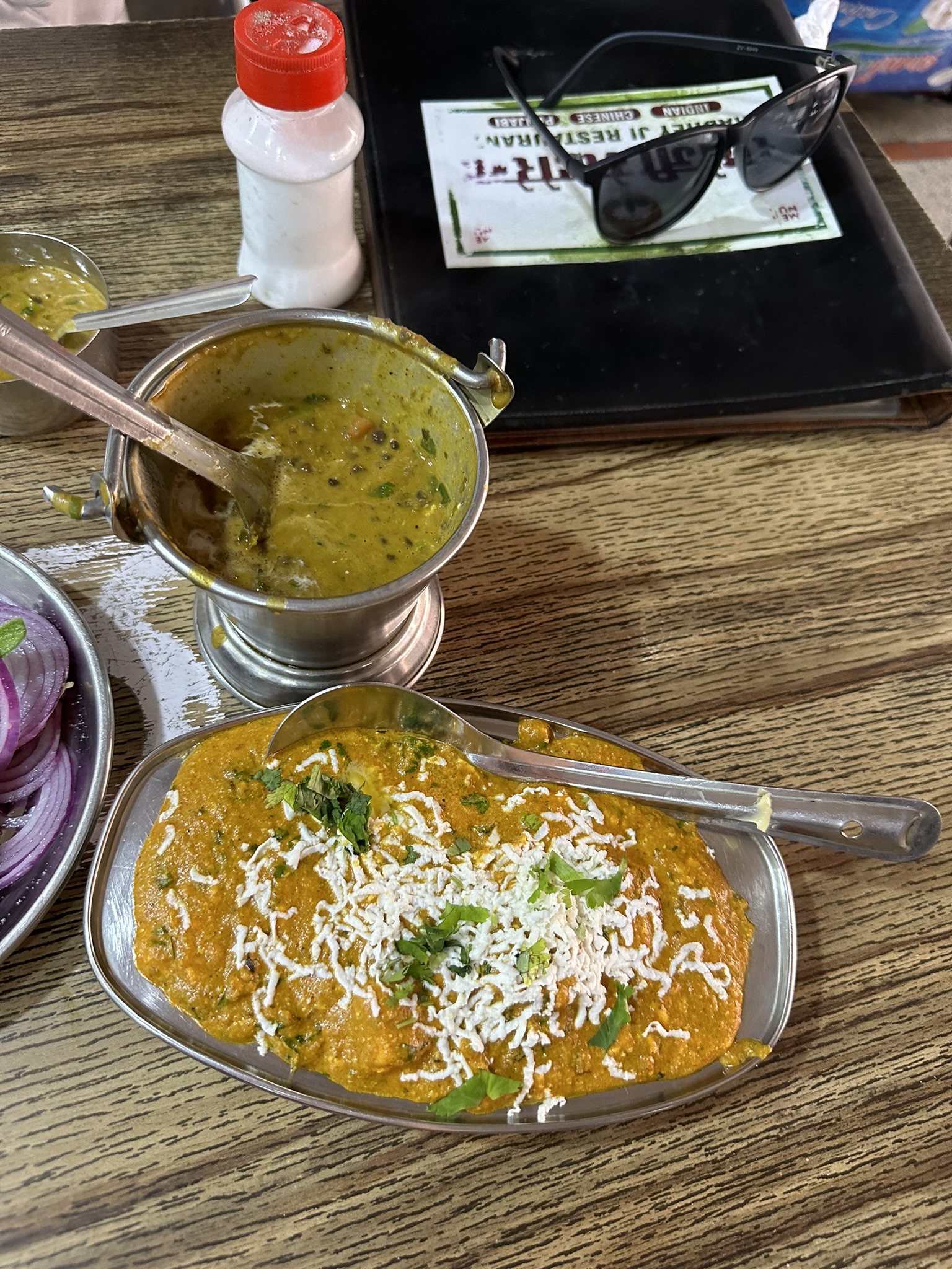 Indyjskie dania: kremowe curry, dal, cebula i przyprawy na drewnianym stole w restauracji